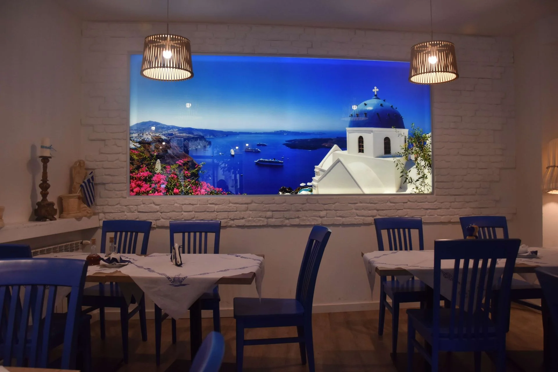 Stoliki przy panoramie Santorini na ścianie.