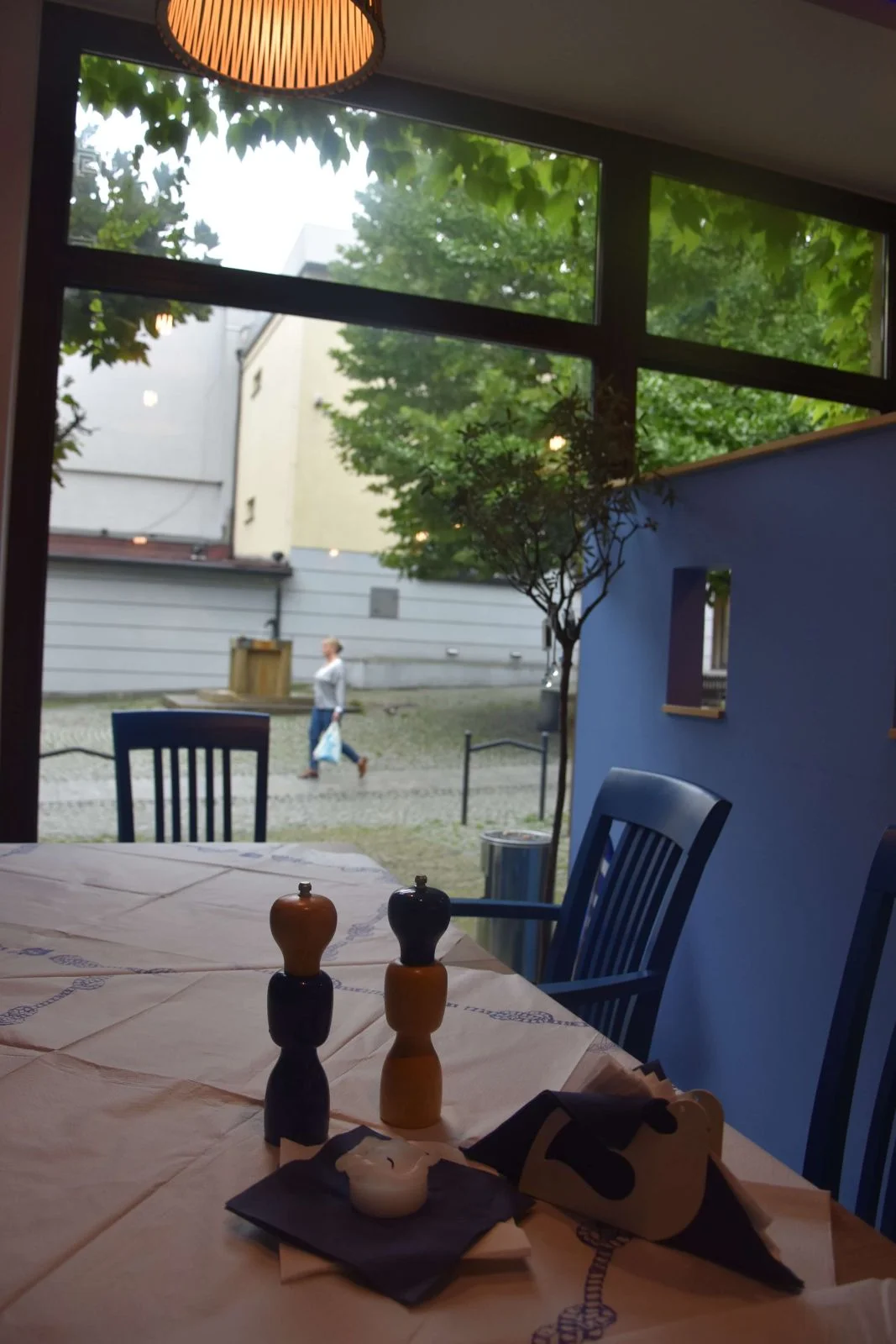 Stolik przy oknie z widokiem na drzewa i ulicę.
